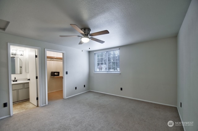 unfurnished bedroom with light carpet, ensuite bathroom, ceiling fan, a spacious closet, and a closet