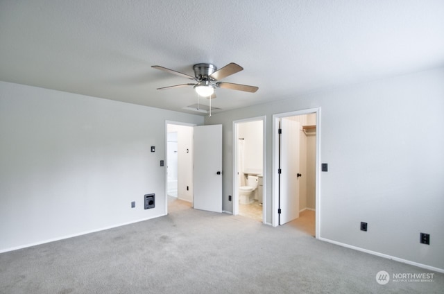 unfurnished bedroom with ensuite bath, ceiling fan, light carpet, and a spacious closet