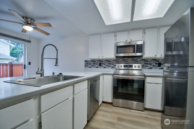 kitchen featuring decorative backsplash, appliances with stainless steel finishes, sink, light hardwood / wood-style flooring, and white cabinetry