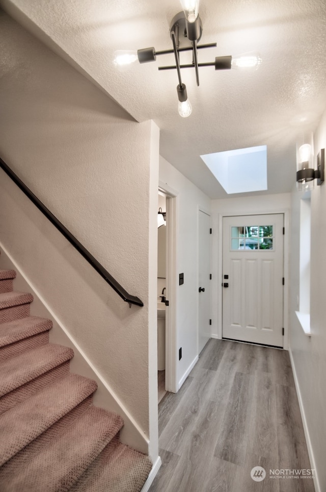 foyer entrance with light hardwood / wood-style flooring and a textured ceiling