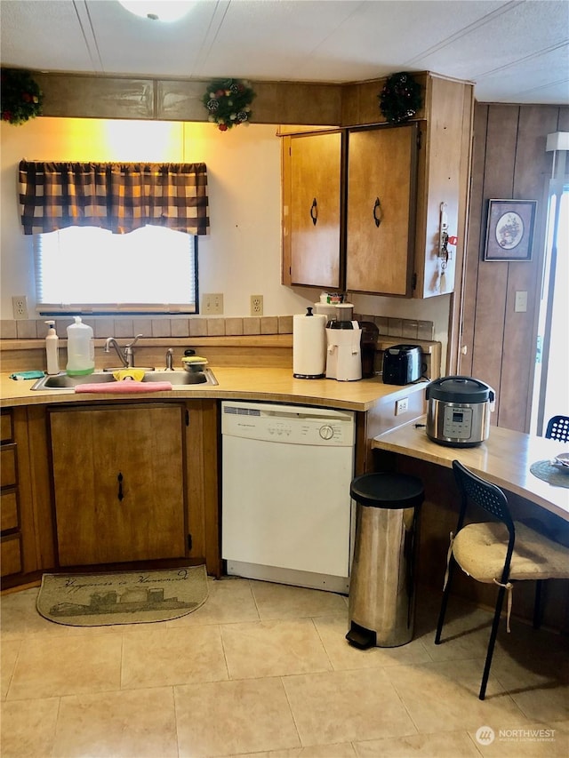 kitchen featuring white dishwasher, sink, and light tile patterned floors