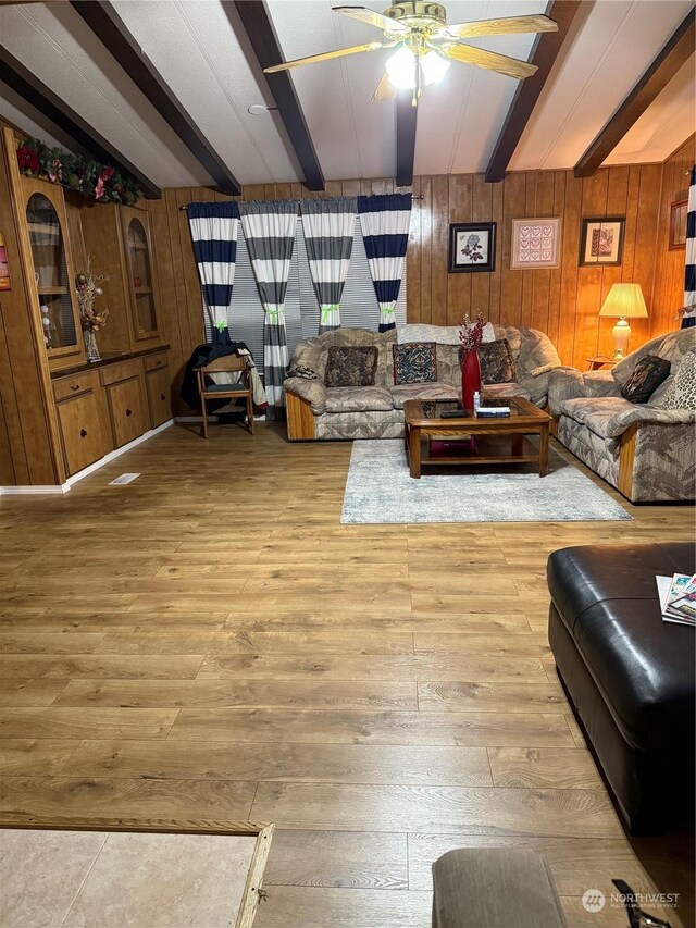 living room with beamed ceiling, ceiling fan, wood walls, and hardwood / wood-style flooring