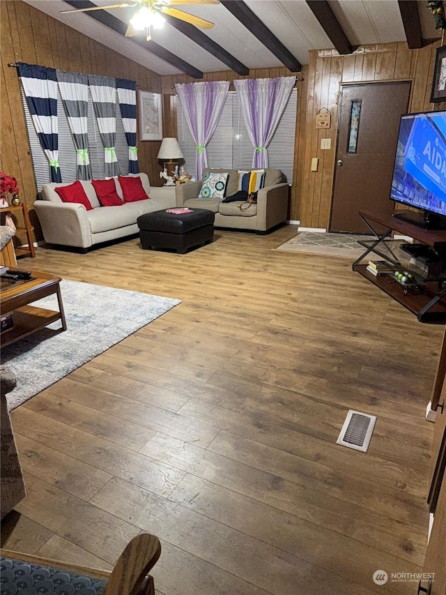 unfurnished living room featuring vaulted ceiling with beams, hardwood / wood-style flooring, and wooden walls