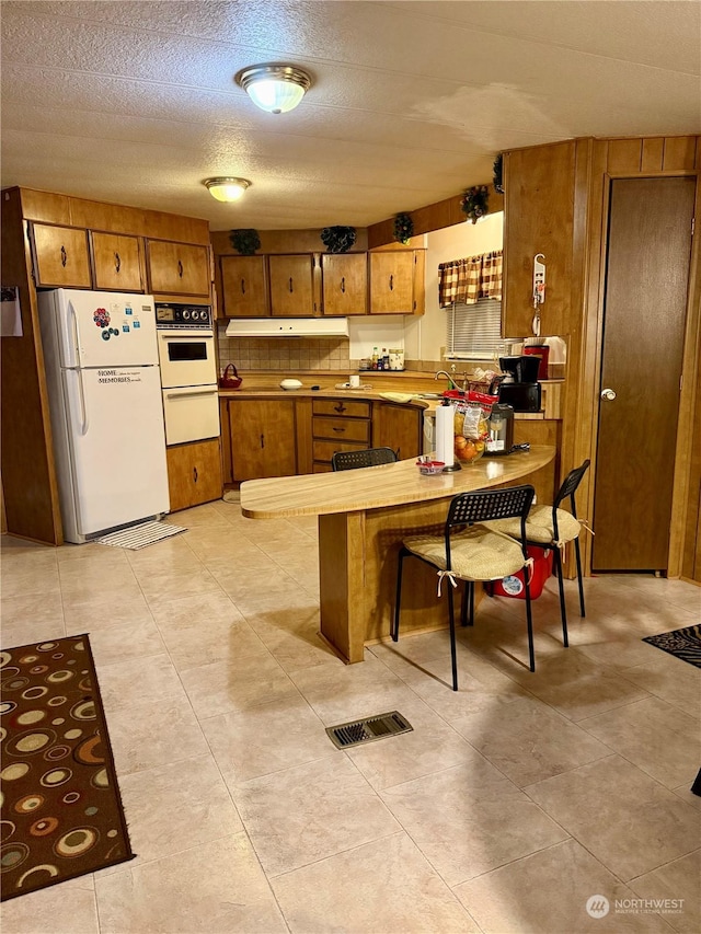 kitchen with white appliances, sink, and a textured ceiling