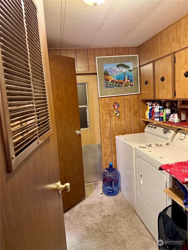 laundry area with washer and dryer, wooden walls, cabinets, light colored carpet, and a textured ceiling