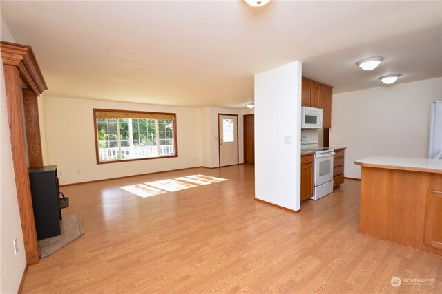 kitchen featuring a wood stove, light hardwood / wood-style flooring, and white appliances