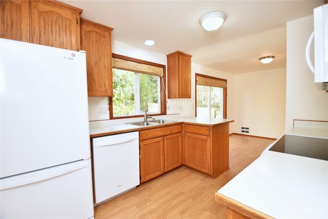 kitchen with white appliances, sink, light wood-type flooring, and kitchen peninsula