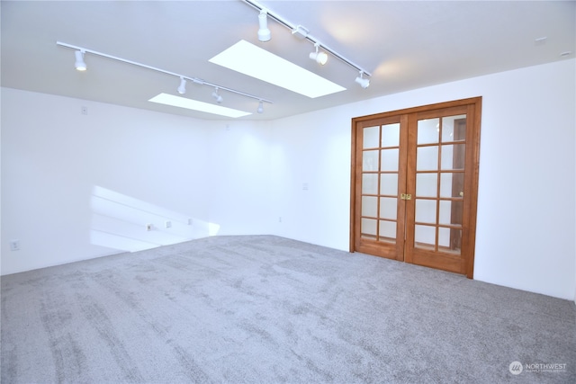 empty room with french doors, carpet floors, a skylight, and rail lighting