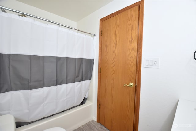 bathroom with wood-type flooring and shower / tub combo with curtain