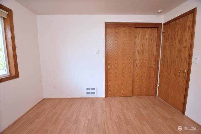 unfurnished bedroom with light hardwood / wood-style floors and a closet