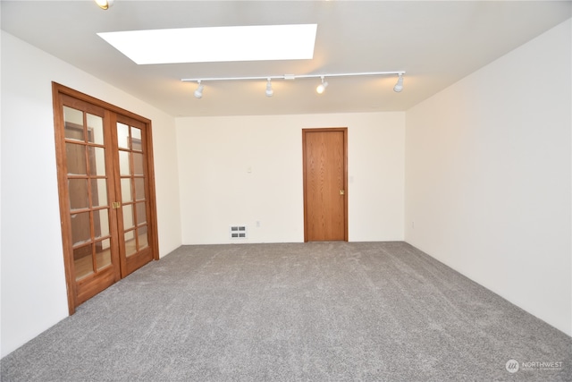 empty room with carpet floors, rail lighting, and a skylight