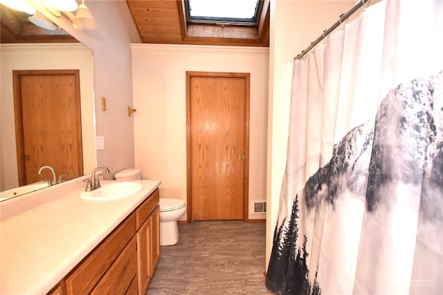 bathroom with wood-type flooring, ornamental molding, vanity, toilet, and a skylight