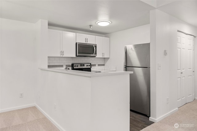 kitchen with kitchen peninsula, backsplash, stainless steel appliances, and white cabinetry