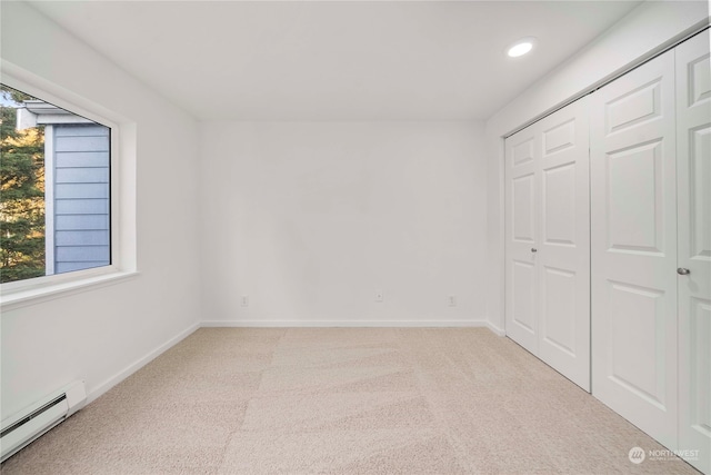 unfurnished bedroom with a closet, light colored carpet, and baseboard heating