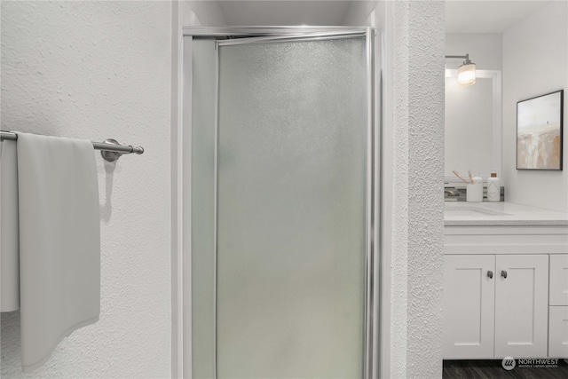 bathroom with hardwood / wood-style floors, vanity, and walk in shower