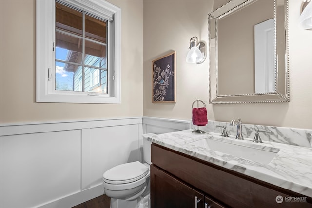 28330 318th Dr SE, Ravensdale, WA 98051 - half bathroom featuring wainscoting, toilet, vanity, a decorative wall, and wood finished floors