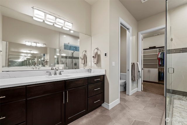 bathroom featuring tile patterned floors, vanity, toilet, and a shower with shower door