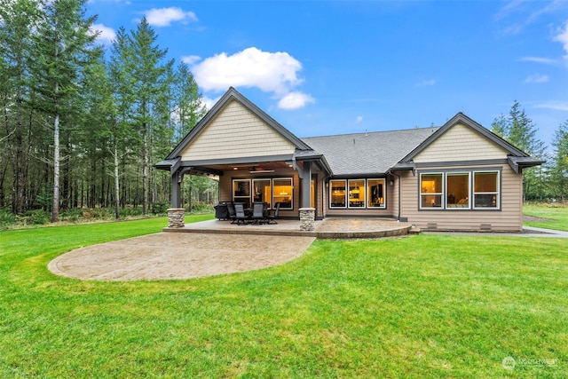 rear view of property with ceiling fan, a patio area, and a yard