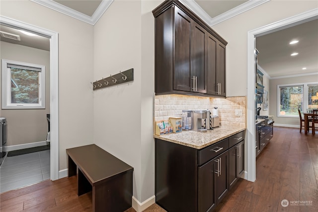 bar with dark hardwood / wood-style floors, light stone counters, dark brown cabinetry, and crown molding