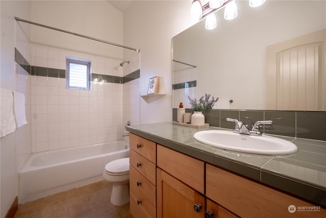 full bathroom with vanity, tile patterned floors, tiled shower / bath, toilet, and tasteful backsplash