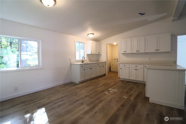 kitchen featuring white cabinets, vaulted ceiling, dark wood-type flooring, and sink