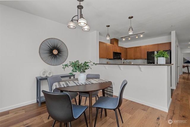 dining room featuring sink, light hardwood / wood-style flooring, and a notable chandelier