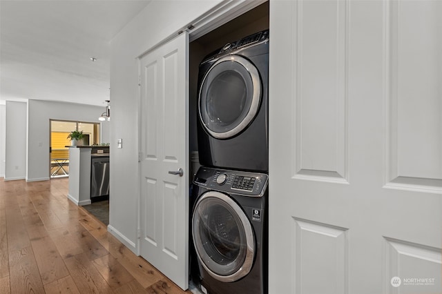 laundry room with stacked washing maching and dryer and hardwood / wood-style flooring