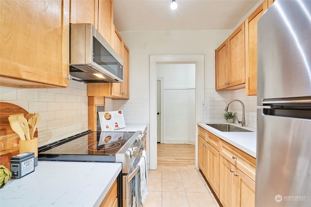 kitchen with sink, appliances with stainless steel finishes, light brown cabinets, light hardwood / wood-style flooring, and decorative backsplash