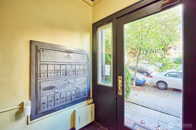 905 NE 43rd St Unit 108, Seattle, WA 98105 - doorway to outside featuring dark tile patterned floors, a textured wall, and mail area