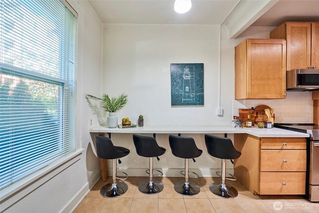 905 NE 43rd St Unit 108, Seattle, WA 98105 - kitchen with appliances with stainless steel finishes, tasteful backsplash, baseboards, light countertops, and a kitchen breakfast bar