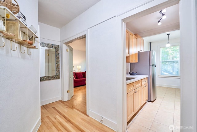905 NE 43rd St Unit 108, Seattle, WA 98105 - kitchen with baseboards, light brown cabinetry, light countertops, light wood-style flooring, and decorative light fixtures