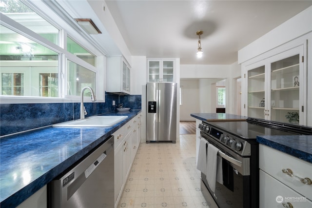 kitchen featuring stainless steel appliances, white cabinets, decorative backsplash, hanging light fixtures, and sink