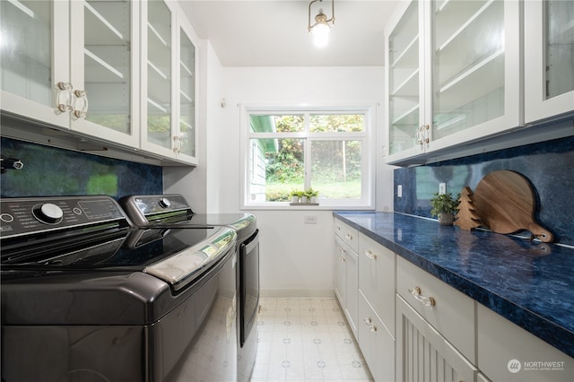 laundry area with separate washer and dryer and cabinets