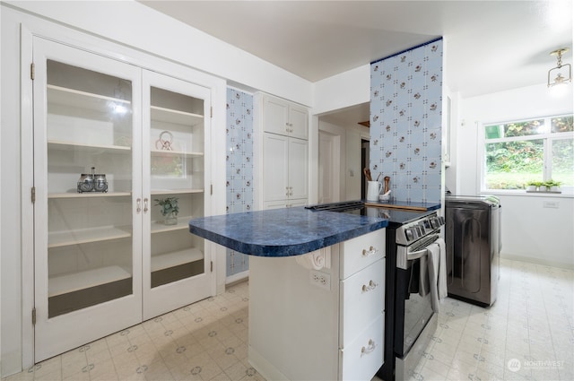 kitchen featuring white cabinets, washer / dryer, a breakfast bar, and stainless steel electric stove