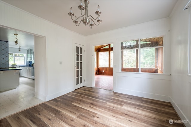 unfurnished room featuring wood-type flooring, a chandelier, and crown molding