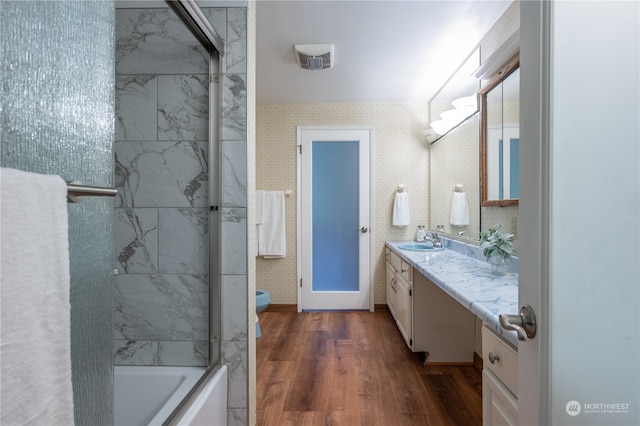 full bathroom featuring toilet, vanity, hardwood / wood-style flooring, and combined bath / shower with glass door