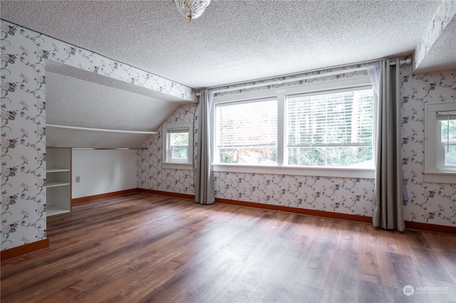 additional living space featuring dark hardwood / wood-style flooring, lofted ceiling, and a textured ceiling