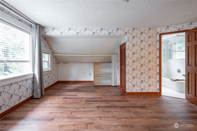 bonus room featuring a textured ceiling, plenty of natural light, hardwood / wood-style flooring, and vaulted ceiling