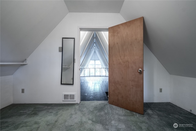 additional living space with dark colored carpet and vaulted ceiling