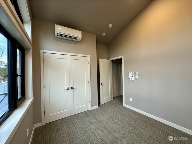 unfurnished bedroom with lofted ceiling, an AC wall unit, a closet, and carpet flooring