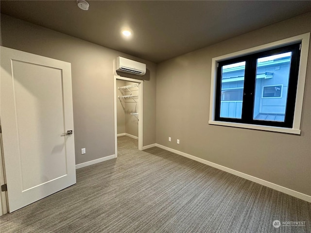 unfurnished bedroom with a walk in closet, a wall mounted air conditioner, a closet, and carpet flooring