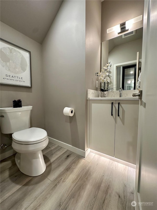 bathroom featuring toilet, vanity, and hardwood / wood-style flooring