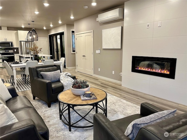 living room with a fireplace, a wall unit AC, and light hardwood / wood-style floors