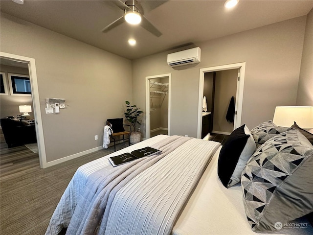 bedroom featuring a closet, ensuite bath, a wall mounted AC, ceiling fan, and a walk in closet