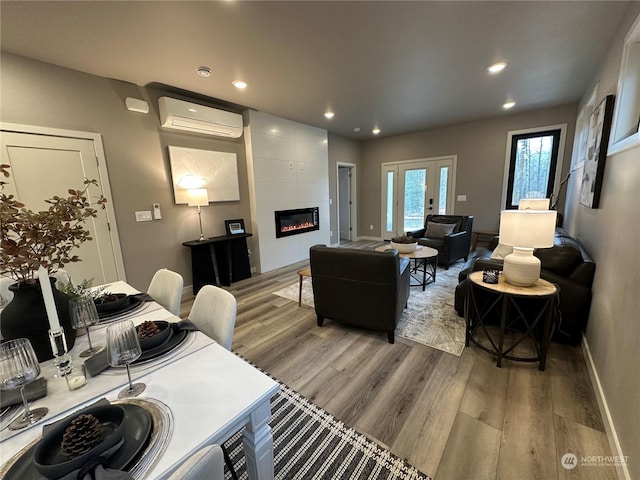 living room with a tiled fireplace, a wall mounted AC, and light hardwood / wood-style floors