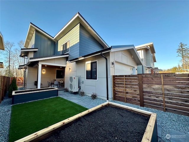 rear view of property with ac unit, a garage, and a yard