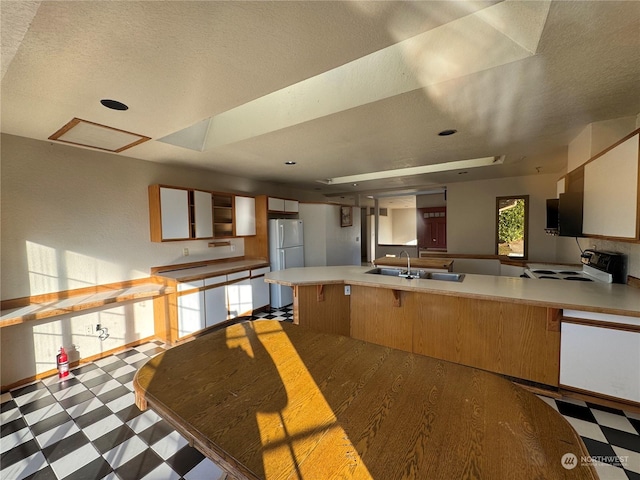 kitchen with sink, a breakfast bar area, range with electric stovetop, kitchen peninsula, and white fridge