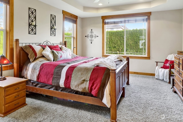 carpeted bedroom featuring ceiling fan and a tray ceiling