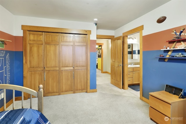 carpeted bedroom with ensuite bathroom, a closet, and sink