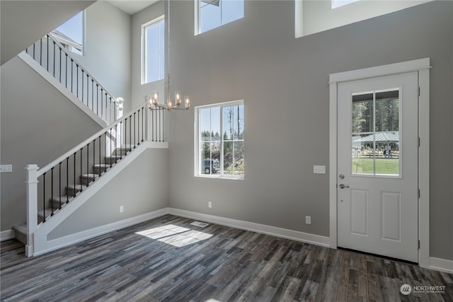 foyer entrance featuring dark wood-type flooring, a notable chandelier, and a towering ceiling